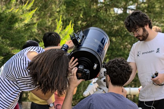 Trois personnes en train d'installer un tub de téléscope sur un trépied